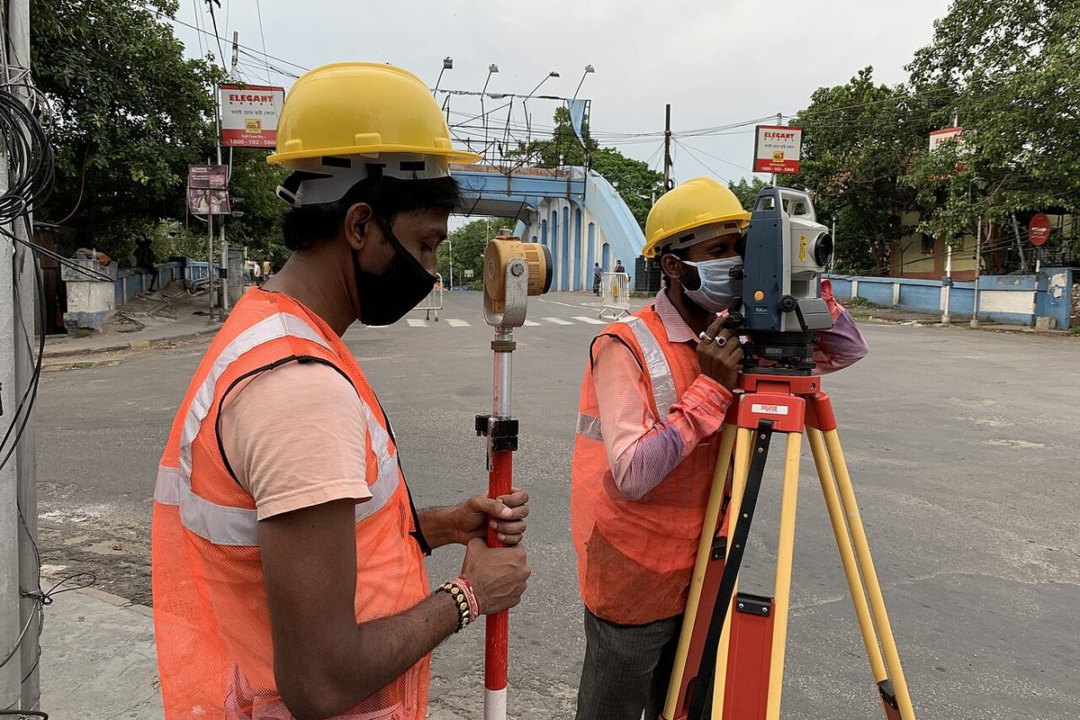 Topógrafos con casco y chaleco operando una estación total