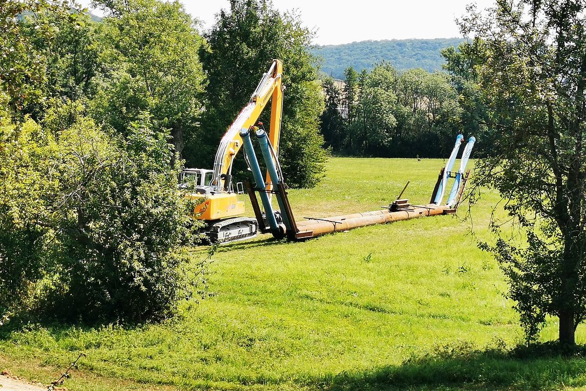 Excavadora tendiendo una tubería de acueducto en un prado